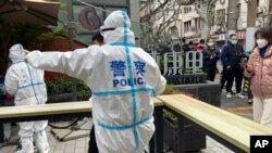 图为2022年4月1日,上海静安区的民警指挥居民排队等待核酸检测。