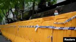 资料照:上海封城后一名女子从围栏后向外张望。(2022年4月13日)