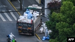 2022年4月20日,穿着防护服的工作人员在上海静安区的一个封闭小区外清理垃圾
