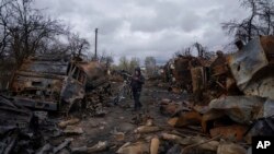 Чоловік везе велосипед вулицею, наповненою знищеною російською військовою технікою, поблизу Чернігова, Україна, неділя, 17 квітня 2022 року. (AP Photo/Євген Малолетка)