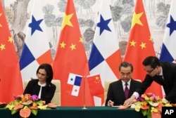 中国外长王毅(右)和巴拿马副总统兼外交部长伊莎贝尔·德圣马洛在北京签署两国建立外交关系的联合公报。(2017年6月13日)