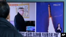在韩国首尔火车站,有人观看电视新闻显示的朝鲜报纸刊登的照片,图片上有朝鲜领导人金正恩和朝鲜发射导弹的景象(2017年2月13日)