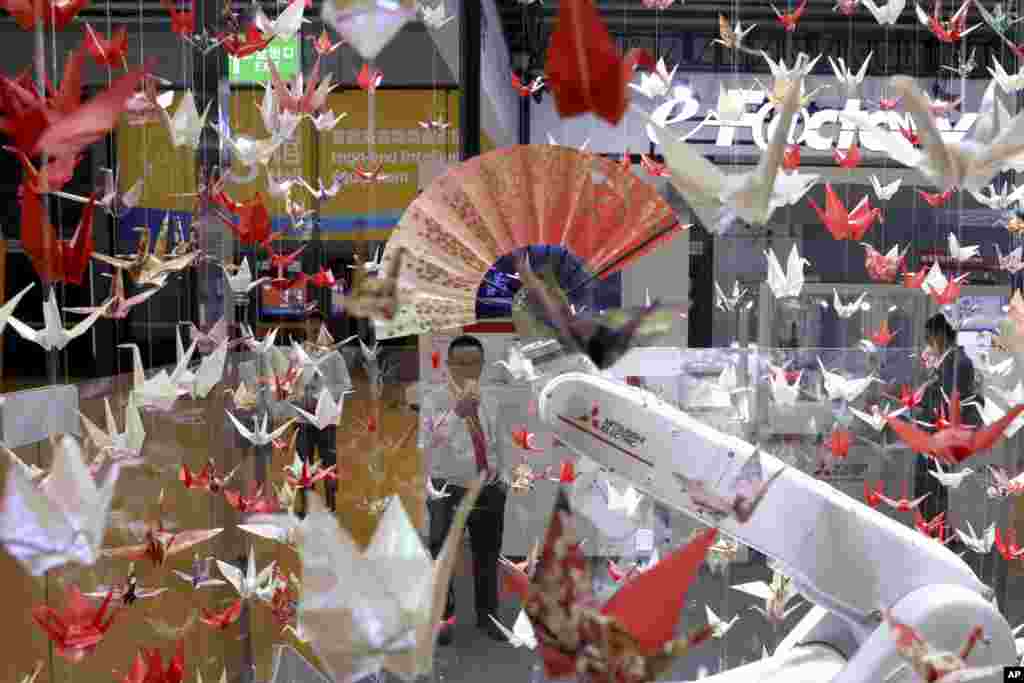 2018年11月5日,在上海举行的中国国际进口博览会上,一台机器人对大量纸鹤挥动纸扇。