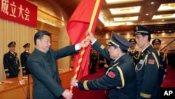 中共领导人习近平在北京举行的中国人民解放军战区成立大会上向火箭军将领、中国防长魏凤和(中)授予军旗。(2015年12月31日)