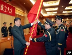 中共领导人习近平在北京举行的中国人民解放军战区成立大会上向火箭军将领、中国防长魏凤和(中)授予军旗。(2015年12月31日)