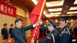 中共领导人习近平在北京举行的中国人民解放军战区成立大会上向时任火箭军将领魏凤和(中)授予军旗。(2015年12月31日)