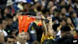 一个小女孩在上海举着两面中国国旗观看布鲁克林篮网队和洛杉矶湖人队的篮球比赛。(2019年10月10日)