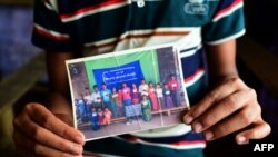 ဒုက္ခသည်စခန်းက ရိုဟင်ဂျာ လူငယ် Mohammad Ayaz က သူ့မိသားစုဝင် ဓါတ်ပုံကို ပြနေစဉ် (ဓါတ်ပုံ- AFP /MUNIR UZ ZAMAN)