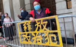 社民连成员曾健成手持标语在终审法院外排队,打算进入内庭旁听支持黎智英 (美国之音/汤惠芸)