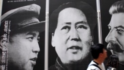 资料照片:在首尔一家韩战展览馆,游人走过战时三名共产党领袖金日成、毛泽东和斯大林的像。(2010年5月21日)