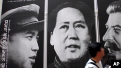 在首尔一家韩战展览馆,游人走过战时三名共产党领袖金日成、毛泽东和斯大林的像(2010年5月21日资料照片)