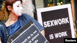 一名戴着面具的妓女举着标语牌参加示威,抗议法国里昂取缔卖淫提案。(2012年7月6日)
