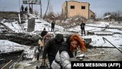 Civilians cross a river via a blown up bridge on Kyiv's northern front on March 1, 2022. (Aris Messinis/AFP)