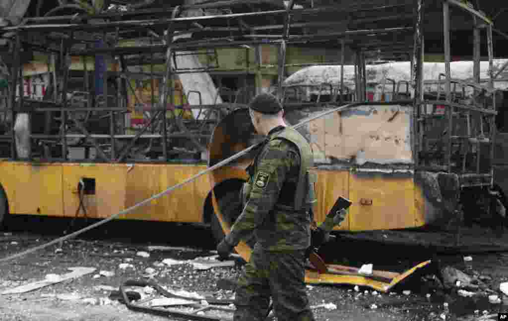 Phiến quân đòi ly khai thân Nga đi ngang qua một trạm xe buýt bị phá hủy sau một vụ pháo kích ở Donetsk, Ukraina, ngày 11/2/2015.  