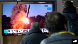 2022年3月20日,在韩国首尔的首尔火车站,人们正在观看一个显示朝鲜火箭发射图像的新闻节目。