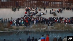 Migrants gather at a crossing into El Paso, Texas, as seen from Ciudad Juarez, Mexico, Dec. 20, 2022.