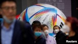 戴着口罩的上海民众走过2022卡塔尔世界杯比赛用球模型。(2022年11月23日)