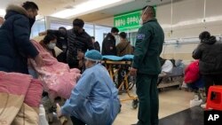 2022年12月22日,河北省霸州廊坊市第四人民医院急诊室,一名患病患者被抬上轮床。