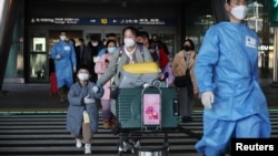 身穿防护服的韩国军人引领一组从中国飞抵仁川国际机场的旅客。(2023年1月12日)