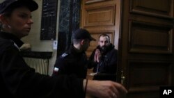 Police officers escort a suspect linked to a deadly bombing in Turkey into court in Sofia, Bulgaria, Nov. 19, 2022.