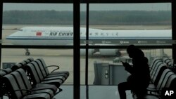 2022年10月29日,中国国际航空一架客机滑行驶过北京首都国际机场时,一名乘客在看手机。(美联社照片)