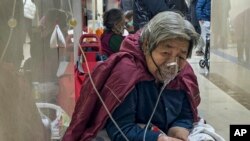 2023年1月5日,一名老年患者在北京急诊病房走廊边使用呼吸机边接受静脉滴注。(美联社照片)
