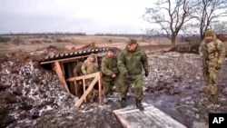 FILE - Russian Defense Minister Sergei Shoigu, center, walks out of a trench, escorted by a group of officers as he inspects Russian troops at an undisclosed location in Ukraine, Dec. 22, 2022..
