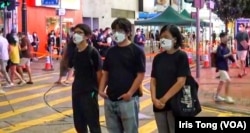 周嘉发(左一)与该党主席陈宝莹(右一)及成员余炜彬,6月4日晚在铜锣湾进行默站快闪悼念六四行动 (社民连社交网站图片)