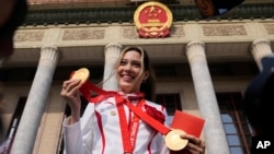 美国出生的中国奥林匹克队明星谷爱凌举着她在北京冬奥会上获得的三枚奖牌在北京人大会堂前拍照留影。(2022年4月8日)
