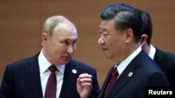 俄罗斯总统普京在乌兹别克斯坦撒马尔罕举行的上海合作组织峰会成员国首脑扩大会议前与中国国家主席习近平交谈。(2022年9月16日)