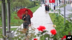 9月14日,一场降雨之后,人们在朝鲜首都平壤中心地区走路。