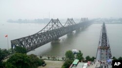 资料照片:在中国丹东,游客走上鸭绿江断桥(右),毗邻连接中国和朝鲜的友谊大桥。(2017年9月9日)