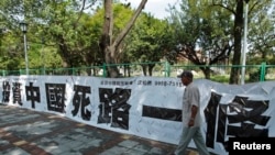 资料照:一名男子走过台北街头悬挂的写有“投资中国死路一条”字样的标语。(2012年8月8日)(路透社)