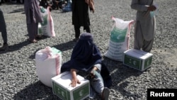 一名阿富汗妇女在首都喀布尔领取沙特阿拉伯提供的人道援助(2022年4月25日)