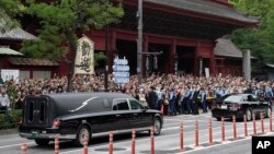 日本前首相安倍晋三的葬礼举行后,运载安倍棺木的灵车离开寺庙,日本民众路旁送行。(2022年7月12日)