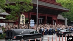 日本前首相安倍晋三的葬礼举行后,运载安倍棺木的灵车离开寺庙,日本民众路旁送行。(2022年7月12日)