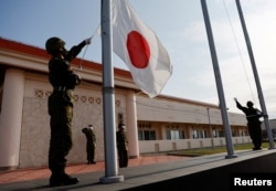 日本冲绳县宫古岛一个军营里的自卫队成员在晚间举行降旗仪式。(2022年4月20日)