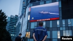 北京市民在观看街头电子屏幕上官媒央视播放的中国军队在台湾附近举行实弹军演的报道。(2022年8月4日)
