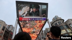北京一家购物中心外面的一个大型屏幕上播放着中国国家主席习近平访问新疆的新闻画面。(2022年7月15日)
