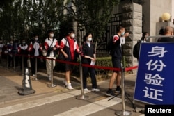 北京考生在进入高考考场前排队等候测量体温。(2022年6月7日)