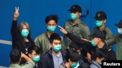 资料照:香港前立法会议员、民主活动人士梁国雄(左后做胜利手势者 )与其他活动人士一起走向一辆囚车,因受国家安全法指控而前往法庭。( 2021年3月4日)