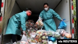 身穿防护服的工作人员把卡车里的蔬菜分发给上海居民。(2022年4月5日)