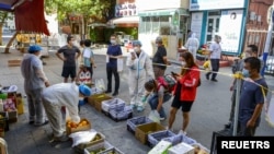 2022年9月5日,中国新疆维吾尔自治区乌鲁木齐市天山区的居民在水果摊位前排队购物