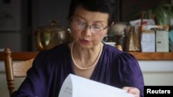 资料照片:2022年7月28日,被监禁的中国人权律师丁家喜的妻子罗胜春在纽约州阿尔弗雷德的家中阅读丁家喜的一封信。(路透社照片)