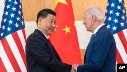 资料照片:2022年11月14日,美国总统拜登和中国国家主席习近平在印度尼西亚巴厘岛举行的G20峰会期间举行会议前握手。(美联社照片)