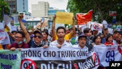 越南胡志明市民众高喊口号,抗议允许外国人在经济特区长期租赁土地的法律草案(2018年6月10日)