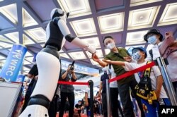 北京举行的2022世界机器人大会上一个机器人与参观者握手。(2022年8月18日)