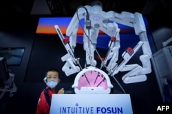 北京举行的2022世界机器人大会上一名儿童在注视一个可以进行外科手术的机械手。(2022年8月18日)