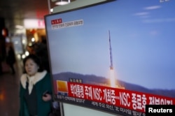 2016年2月7日,韩国首尔火车站,一位旅客走过正在显示北朝鲜发射远程火箭新闻的电视屏幕。