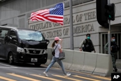 资料照:在美国驻港澳总领事馆外的一次抗议活动中一名抗议者举着一面美国国旗过马路。(2020年7月4日)